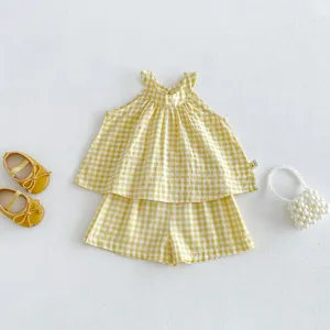 Vista dettagliata del set top halter e pantaloncini a quadretti gialli per bambina con accessori.
