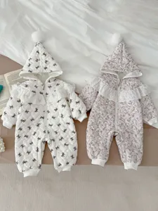 Detalle de mameluco de invierno acolchado para bebé con capucha, lindos lazos y tela cálida.
