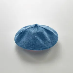 Infant blue knit beret detail view, soft breathable solid color baby hat close-up shot.