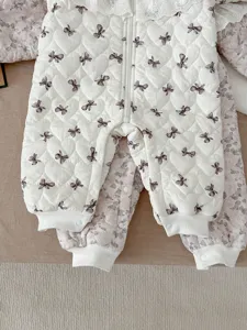 Vista detallada de mameluco acolchado para bebé con lazos bonitos y cuello de encaje.