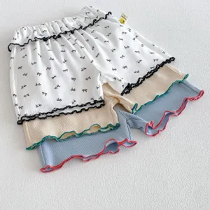 Dettaglio pantaloncini a coste per neonati, orlo volant, tessuto morbido per comfort.
