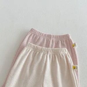 Close-up detail of soft waffle knit toddler pants in pink and beige with cute side labels.