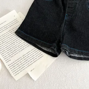 Vista dettagliata di pantaloncini in denim scuro per bambini con cuciture blu, tessuto.