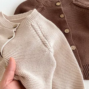 Primo piano del cardigan in maglia per neonato con bottoni in legno, dettaglio.