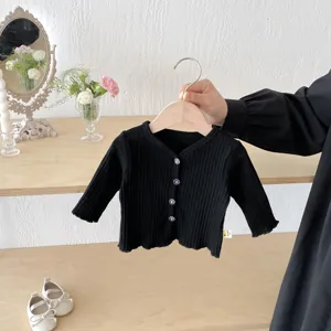 Gros plan sur le gilet tricot noir pour bébé, texture côtelée et boutons pour les petites filles.
