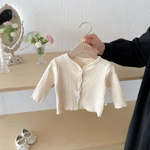 Cardigan tricoté côtelé bébé vue de détail, couleur crème douce avec boutons, pièce quotidienne.