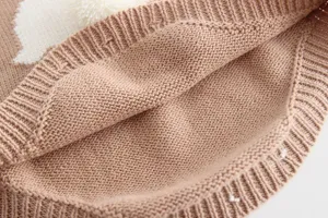 Close-up view of infant knit romper detail, showing soft cotton texture and cute pom-pom.