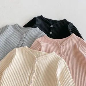 Gros plan sur les détails de cardigans bébé en tricot côtelé doux aux coloris variés.