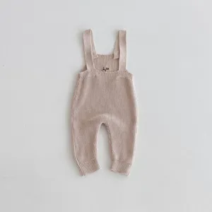 Dettaglio tutina neonato in maglia, cotone morbido, simpatica salopette neutra per bambini.