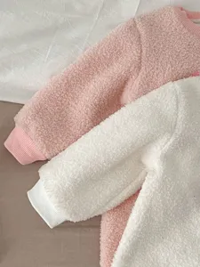 Detailed view of soft fleece baby romper fabric and ribbed cuffs in pink and white.