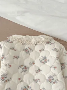 Cute floral quilted baby jacket detail, soft lace collar, warm winter infant clothing close-up