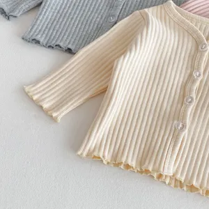 Vue détaillée du gilet en tricot côtelé pour bébé avec ourlet volanté et boutons.