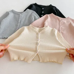 Détail de gilet en tricot pour bébé montrant une texture côtelée douce et extensible.