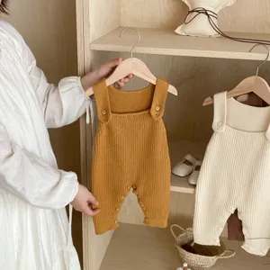 Baby knit romper detail, autumn infant ribbed overalls with wooden buttons and straps.