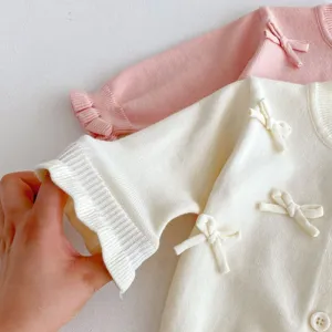 Detail view of baby knit cardigan with cute bows and soft texture for infant girls autumn.