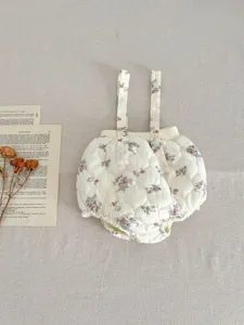 Close-up detail of infant quilted floral romper straps, cozy beige winter baby clothing design.