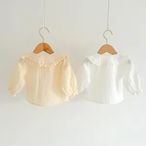 Detail view of baby girl long sleeve cotton ruffle collar shirts in soft yellow and white.