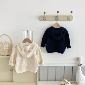 Vue détaillée du gilet en tricot pour bébé à capuche avec oreilles d'ours sur décor.