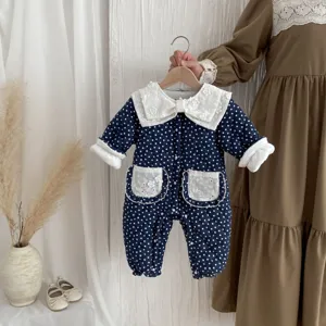 Detailed close-up of cute baby winter romper with white lace collar and polka dots.