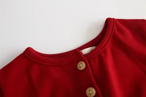 Dettaglio colletto abito rosso per bambini con bottoni in legno e tessuto morbido in primo