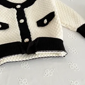 Kleinkind Strickjacke Detailansicht, schwarz-weiß Block, Perlenknöpfe, eleganter Stil.