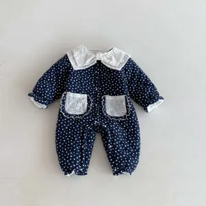 Detailed view of cute baby winter quilted jumpsuit, dark blue polka dot fabric, lace collar.