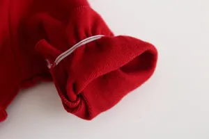 Dettaglio manica abito rosso neonato primo piano, tessuto morbido polsino elastico principessa.