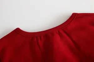 Dettaglio colletto abito rosso per neonata, primo piano mostra tessuto morbido e cuciture.