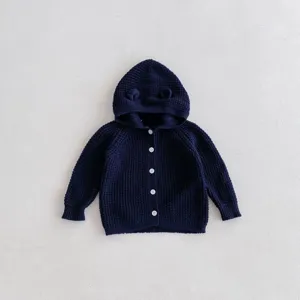 Vue détaillée du gilet en tricot bleu foncé pour bébé avec capuche, oreillettes et boutons.
