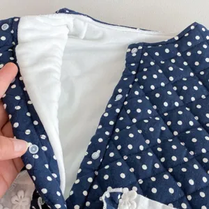 Infant winter baby jumpsuit detail shot, navy blue polka dot fabric with warm fleece lining.