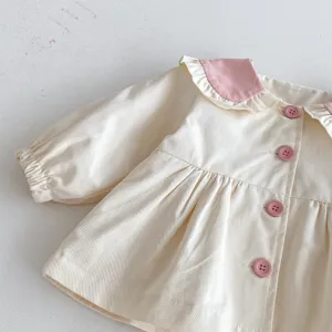 Detalle de chaqueta de otoño para niña con cuello rosa contrastante, volantes y botones.