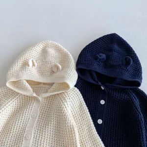 Gros plan d'un gilet en tricot pour bébé avec des oreilles d'ours et des boutons, détails.