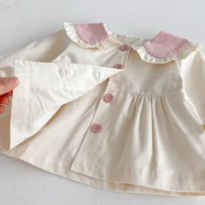 Detalle de chaqueta de algodón beige para niña, cuello con volantes y bonitos botones.