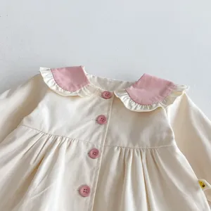 Detalle de chaqueta de algodón para niña pequeña, abrigo crudo con volantes y botones rosa.