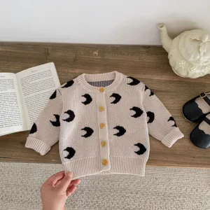 Close-up detail of baby knit cardigan featuring all-over black moon print and wooden buttons.