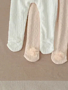 Close-up detail of baby fleece-lined tights featuring cute flower decoration, soft texture.