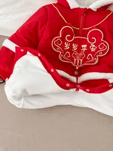 Close-up of baby red winter jumpsuit lining, embroidered Chinese New Year auspicious blessing details.