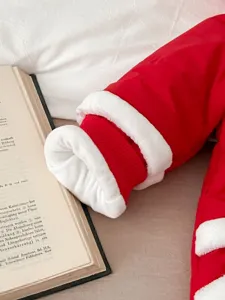 Detail view of baby red winter jumpsuit cuff with soft white plush trim, warm padded design.