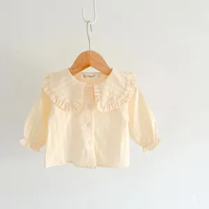 Close-up detail of infant baby girl long sleeve blouse with cute ruffles collar and buttons.