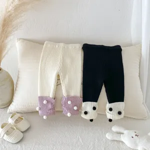 Baby Strickleggings Detail, süße Bommel-Bündchen, weiches Baumwollmaterial für Mädchen.