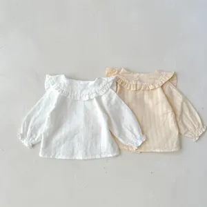 Close-up detail of infant cotton long sleeve blouses with ruffled collars, white and yellow.
