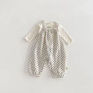 Süßes Baby Mädchen zweiteiliges Set langarm weißes T-Shirt und schwarze Pünktchen Latzhose.