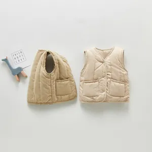 Detailed shot of kids beige quilted vest with front pockets, cozy winter children apparel.