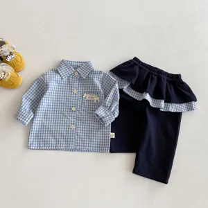 Completo autunnale da bambina con camicia a maniche lunghe a quadri blu e pantaloni abbinati.