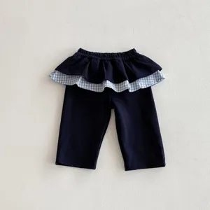Vista dettagliata di pantaloni blu scuro per bambina con elegante cinturino peplum a quadri.