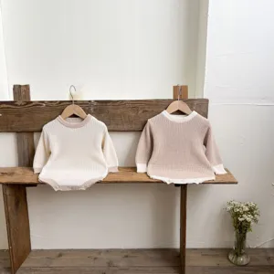 Detailansicht süßer Baby Strick-Strampler auf einer Bank, gemütlicher Herbst-Look für Babys.