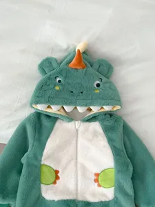 Vista dettagliata della tutina peluche da dinosauro per neonati con morbido cappuccio.