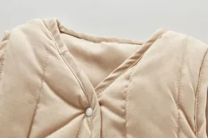 Close-up detail of infant quilted beige vest collar and button, soft warm winter toddler wear.