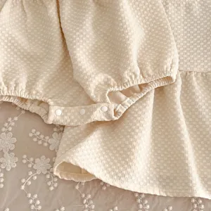 Gedetailleerd shot van baby meisjes wafel romper jurk met schattige volants en drukknoppen.