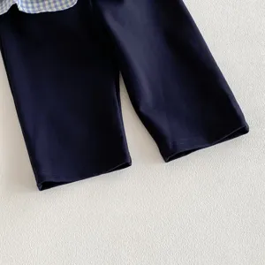 Dettaglio di pantaloni autunnali e camicia a quadri per bambina, finiture pulite.